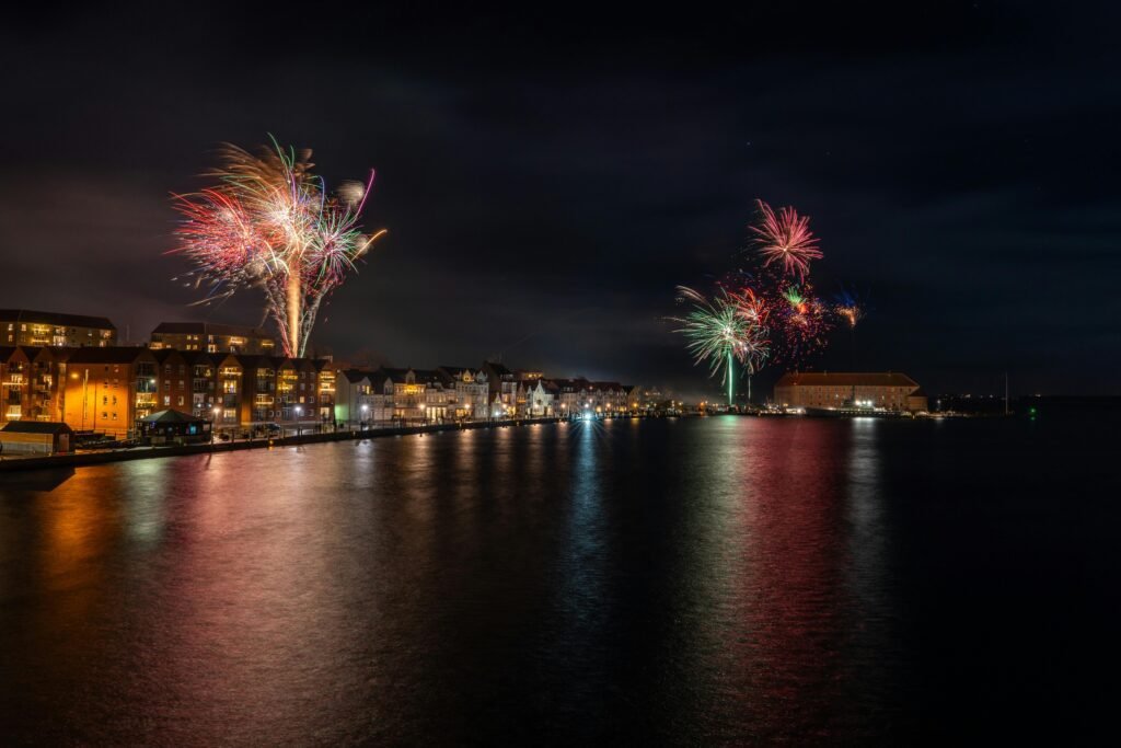 Stunning fireworks display over Sønderborg harbor with vibrant reflections on the water.