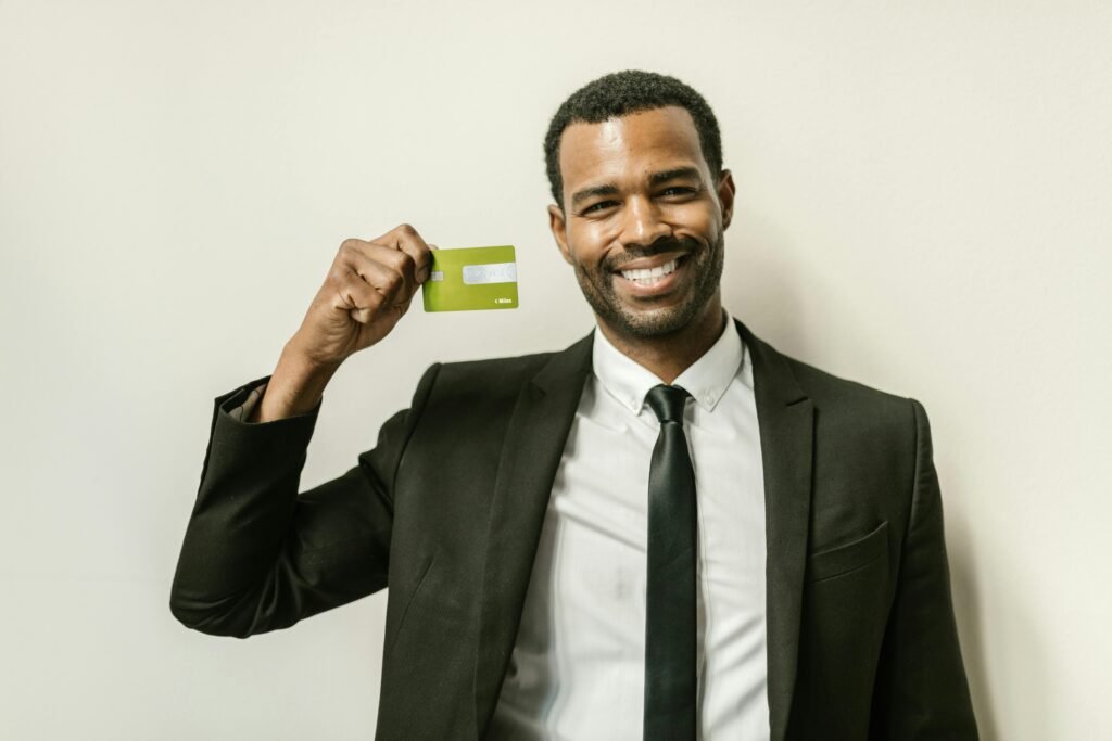 Smiling businessman in a suit displaying a green credit card after opening a bank account